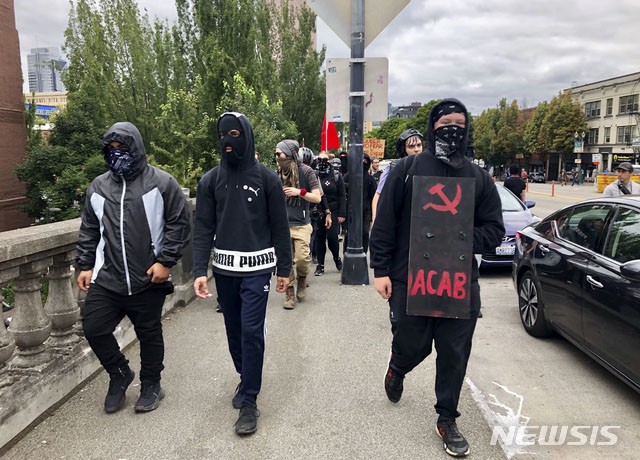 ▲ 지난해 8월 오레곤주 포틀랜드에서 시위를 벌일 당시 안티파 조직원의 모습. 후드 달린 검은 옷과 검은 마스크, 손에 검은 우산, 배낭까지 메고 있으면 거의 확실하다. ⓒ뉴시스 AP. 무단전재 및 재배포 금지.