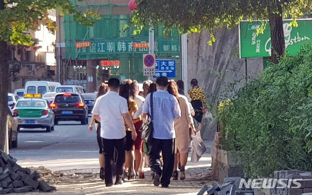 ▲ 아침 단체로 출근하는 중국 단둥 파견 북한 근로자들. 맨 뒤 남성들은 감독관으로 추정된다. ⓒ뉴시스. 무단전재 및 재배포 금지.