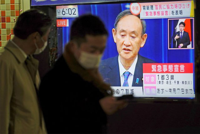 ▲ 스가 요시히데 일본 총리가 긴급사태 선언과 관련한 기자회견을 하는 모습을 한 시민이 지켜보고 있다. ⓒ뉴시스 AP. 무단전재 및 재배포 금지.