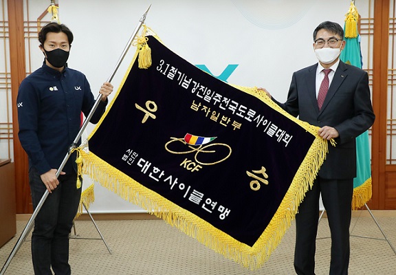 ▲ LX 김정렬 사장(오른쪽)과 LX사이클팀 장선재 코치가 3·1절 기념 강진투어 전국도로사이클대회 남자일반부 단체종합 우승 깃발을 들고 있다.ⓒLX