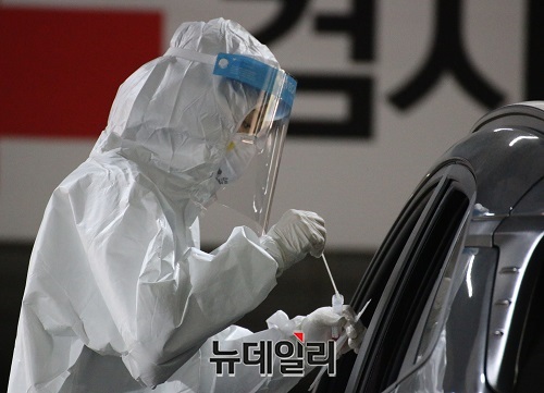 ▲ 방역당국이 세종시 어진동에 설치된 코로나19 선별진료서에서 차량에 탑승한 시민에게 검채를 체취 하고 있다.ⓒ이길표 기자
