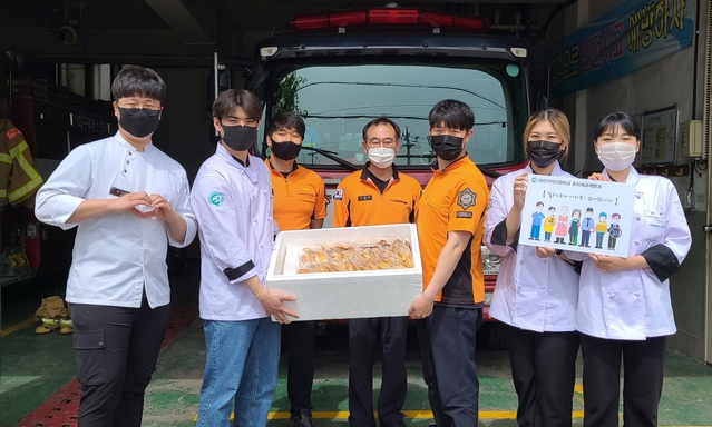 ▲ 영진전문대 조리제과제빵과 학생들이 실습수업에서 만든 빵을 대구북부소방서 복현119지역대 소방대원들에게 전달했다. 사진은 빵을 전달하며 소방대원 응원에 나선 학생들이 소방대원들과  포즈를 취한 모습.ⓒ영진전문대