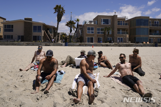 ▲ 27일(현지시간) 미 캘리포니아주 샌디에이고의 한 해변에서 마스크를 쓰지 않은 남성들이 모여 있다. 미국 질병통제예방센터(CDC)는 코로나19 백신 접종을 완료한 경우 야외에서 마스크를 쓰지 않아도 된다고 발표하며 야외 마스크 착용에 대한 지침을 완화했다. ⓒ뉴시스
