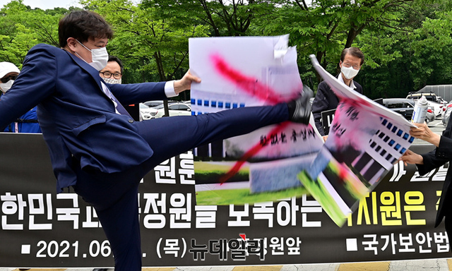 ▲ '국가보안법 수호 자유연대'가 국정원 새 원훈석 사진에 붉은 페인트로 'X'를 그린 뒤 발로 차 부수는 퍼포먼스를 하고 있다. ⓒ정상윤 기자