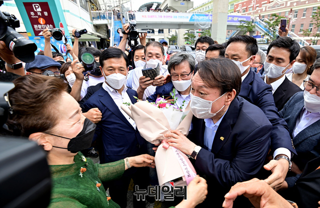 ▲ 대선 출마를 선언한 윤석열 전 검찰총장이 20일 오후 대구 중구 서문시장을 방문해 상인회관계자에게 꽃다발을 받고 있다. 윤 전 총장은 이날 2.28기념탑 참배를 시작으로 대구를 방문해 서문시장, 동성로, 동산병원, 창조경제혁신센터 등을 방문했다.ⓒ대구=정상윤 기자