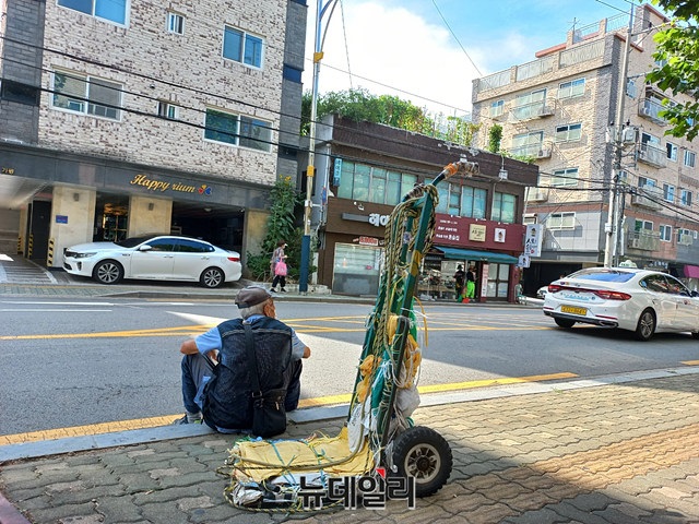 ▲ 폐지수거 노인이 폐지를 고물상에 판 뒤 갓길에 앉아 쉬고 있다. ⓒ이건율 기자