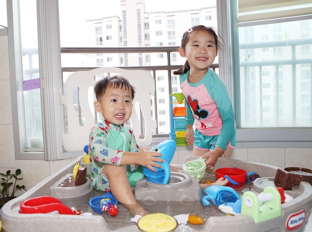 ▲ 장서은(6)·주현(3) 남매는 장난감도서관에서 대여한 ‘워터 테이블’과 ‘상어잡기’ 장난감으로 자신의 집 베란다를 ‘베터파크’로 꾸며놓고 물놀이 삼매경에 빠졌다.ⓒ칠곡군