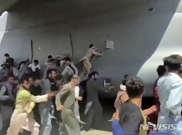 ▲ 16일(현지시간) 아프가니스탄 카불의 하미드 카르자이 국제 공항에서 활주로를 따라 이동하는 미 공군 C-17 수송기에 아프간 사람들이 매달리고 있다. 탈레반이 점령한 아프간을 탈출하려는 아프간 시민 수천 명이 이날 공항 활주로에 몰려들었다. 일부는 필사적으로 미군 항공기에 매달리다가 추락해 사망한 것으로도 알려졌다.ⓒ뉴시스