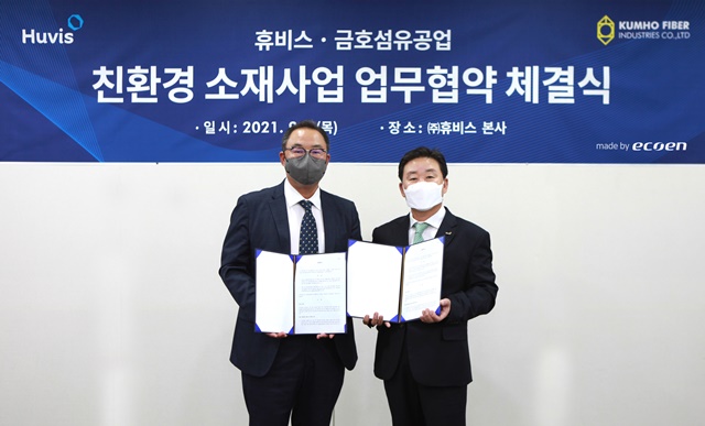 ▲ 강승범 금호섬유공업 사장(좌)과 신유동 휴비스 사장이 업무협약식에서 기념촬영을 하고 있다. 뒤쪽 현수막은 휴비스의 생분해 섬유 '에코엔'으로 제작됐다. ⓒ휴비스