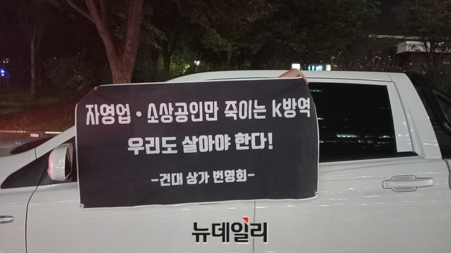 ▲ 전국자영업자비상대책위원회 (자대위)의 본래 집결지인 여의도 신한금융투자타워 인근에서 한 자영업자가 '자영업‧소상공인만 죽이는 K-방역, 우리도 살아야 한다'는 문구의 현수막을 들고 있다. ⓒ이건율 기자
