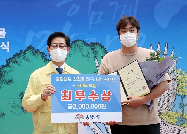 ▲ 양승조 충남도지사(좌측)이 도 상징물인 소나무 부분에 최우수상 수상자인 박성민씨에게 상을 전달한 뒤 기념촬영을 하고 있다.ⓒ충남도