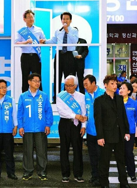 ▲ 임씨가 검은색 정장을 입고 2010년 당시 이재명 성남시장 후보 선거유세 현장에 서 있는 모습. ⓒ페이스북 캡쳐