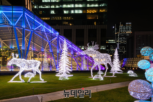 ▲ 빛 축제인 '2021 라이팅 페스티벌'을 찾은 관람객이 22일 저녁 서울 여의도 IFC서울 외부 광장인 노스파빌리온에서 포즈를 취하고 있다. 행사는 2022년 1월 16일까지 진행한다. ⓒIFC서울