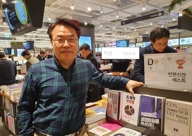 ▲ 자신이 쓴 '적폐몰이, 공영방송을 무너뜨리다'가 진열된 한 서점 앞에서 포즈를 취하고 있는 김도인 방문진 이사. ⓒ뉴데일리