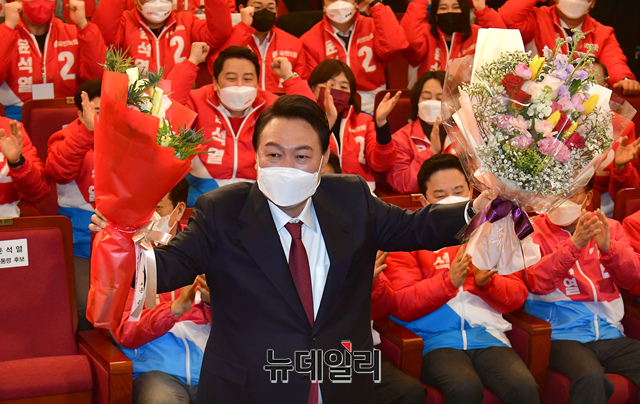 ▲ 윤석열 국민의힘 대통령 후보가 10일 당선이 확정된 후 국회도서관에 마련된 국민의힘 대선 상황실을 찾은 모습이다. 지지자들로부터 받은 축하 꽃다발을 양 손에 들고 당선 축하에 화답하고 있다.ⓒ뉴데일리 DB