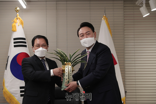 ▲ 윤석열 대통령 당선인이 10일 오후 서울 여의도 국민의힘 당사에서 유영민 대통령 비서실장에게 문재인 대통령의 축하난을 받고 있다.