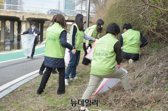 ▲ 31일 서울 서초구 농협하나로마트 양재점 인근 여의천에서 농협유통 전무이사 김태룡(사진 가운데 대형 피켓) 및 직원들이 여의천 환경정화를 위해 플로깅 캠페인을 실시했다. ⓒ농협유통