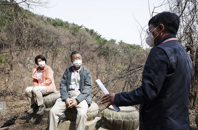 ▲ 지난 5일 북악산 남측 산책로에서 법흥사 대웅전 연화문 초석에 앉아 설명을 듣는 문재인 대통령 내외. ⓒ청와대 제공.