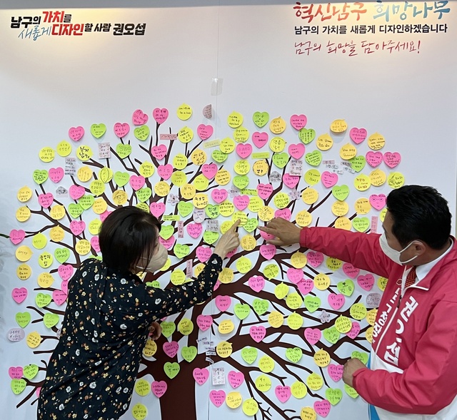 ▲ 21일 권오섭 남구청장 예비후보 선거사무소를 방문한 지지자가 ‘혁신남구 희망나무’에 메모지를 붙이고 있다.ⓒ권오섭 예비후보 선거사무소