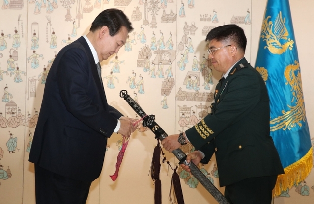 ▲ 윤석열 대통령이 27일 서울 용산구 대통령실 청사에서 신희현 육군 2작전사령관에게 삼정검에 수치를 달아주고 있다. ⓒ대통령실 제공