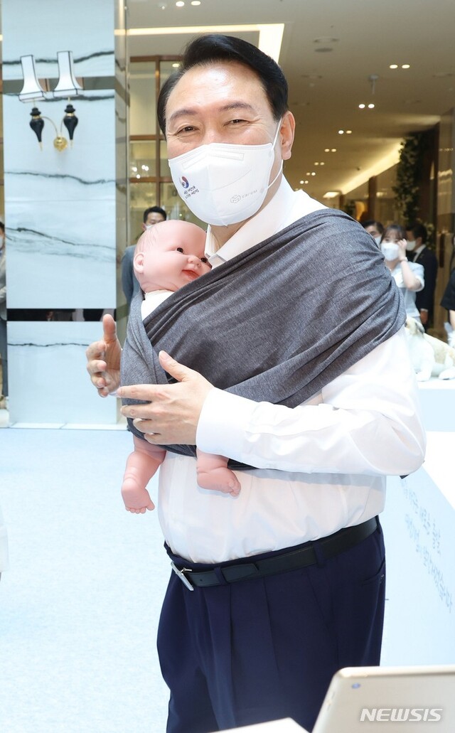 ▲ 윤석열 대통령이 5일 서울 여의도 중소기업중앙회관에서 열린 제1회 여성기업주간 개막식에 참여해 참여 기업이 개발한 목이 편한아기띠를 착용해보고 있다. ⓒ뉴시스