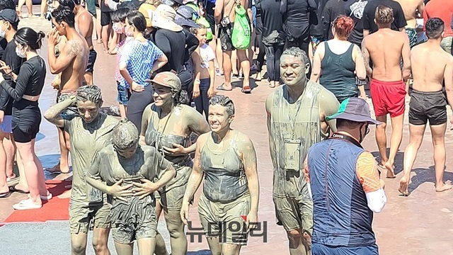 ▲ 2022보령해양머드박람회장에 외국인 가족이 머드를 온 몸에 바른 채 이동하고 있다. ⓒ김정원 기자