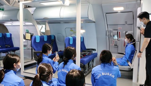 ▲ 에어부산 진로체험 프로그램인 '꿈담기 드림교실'에 참여한 학생들이 항공기 비상구 작동법을 배우고 있다. ⓒ에어부산
