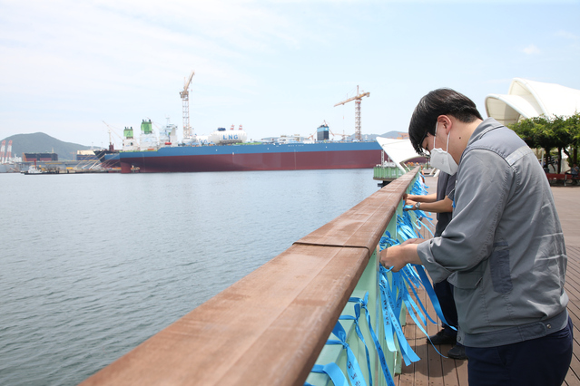 ▲ 대우조선해양 직원들이 1도크 정상화를 기원하는 메시지가 적힌 리본을 달고 있다. ⓒ대우조선해양
