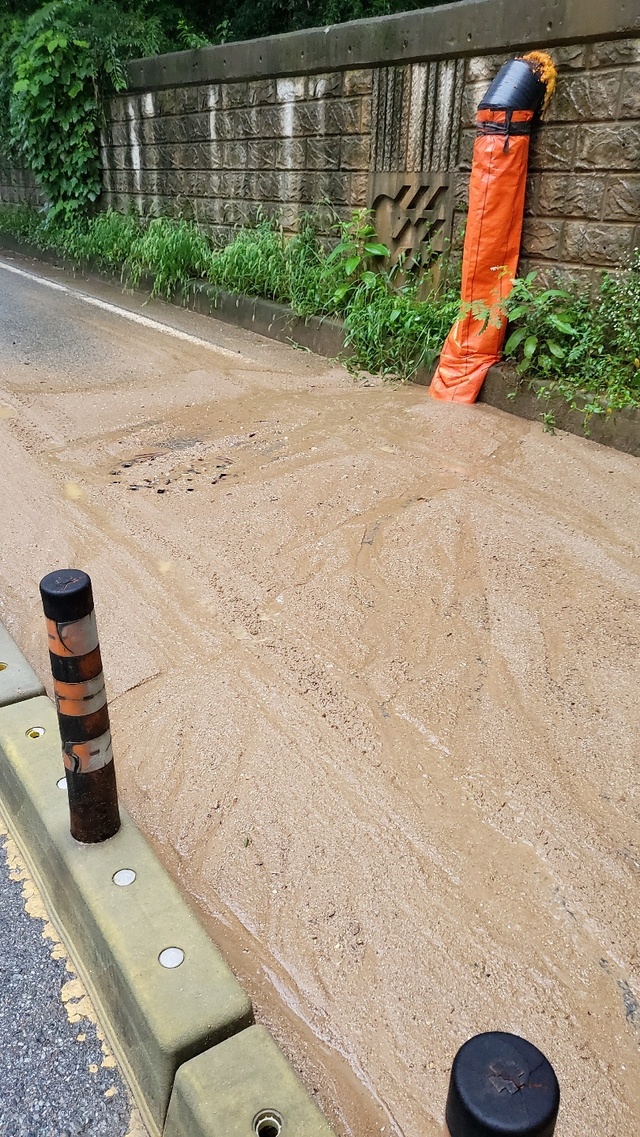 ▲ 11일 충남 천안시 동남구 일봉산 아래 위치한 2차선 도로에 토사가 유출된 모습이다. 이 곳은 지대가 낮아 일봉산에서 비만 내리면 토사가 흘러 내리고 있다.ⓒ독자제공