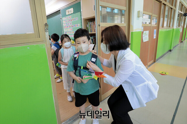 ▲ 일선 초등학교들이 여름방학을 맞은 지난달 15일 서울 중구 청구초등학교에서 선생님이 방학식을 마친 학생들에게 코로나19 예방을 당부하며 하교를 돕고 있다.ⓒ강민석 기자