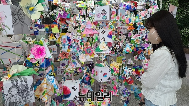 ▲ 충남 천안시노인종합복지관 등이 제77주년 광복절 의미를 되새기기 위해 전시하고 있는 모빌 작품을 천안시청 한 여성 공무원이 관심있게 살펴보고 있다.ⓒ김정원 기자