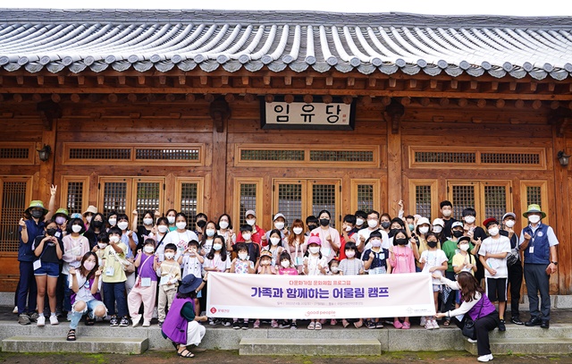 ▲ '다문화 어울림 가족 캠프'에 참여한 가족들이 국립아세안휴양림 전통가옥 앞에서 기념촬영을 하고 있다. ⓒ롯데건설