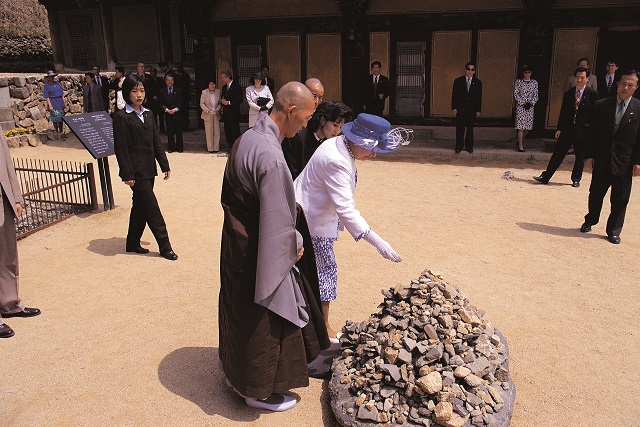 ▲ 엘리자베스 여왕이 봉정사 목조건물인 극락전 앞 돌탑에 돌멩이 하나를 올리고 있다.ⓒ안동시