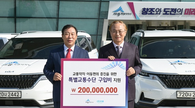 ▲ 박한길 애터미 회장(오른쪽)이 15일 세종시청 현관앞에서 장애인콜택시 구입비 2억 원을 최민호 시장에게 전달하고 기념촬영을 하고 있다.ⓒ세종시