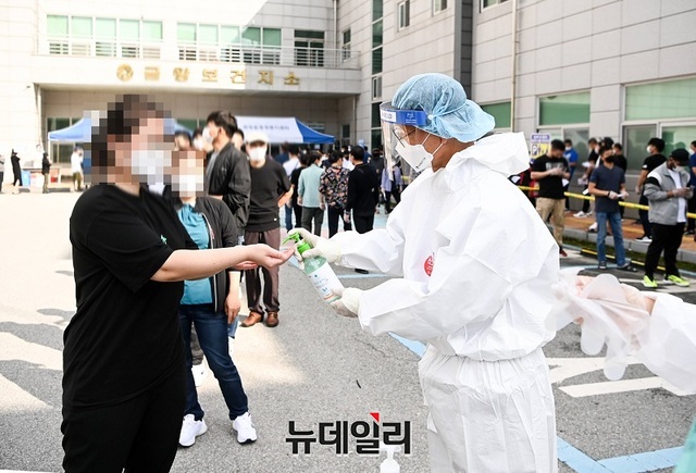 ▲ 보건소 방역요원이 외국인에게 코로나19 예방을 위해 손세정을 뿌려주는 장면.ⓒ뉴데일리 D/B