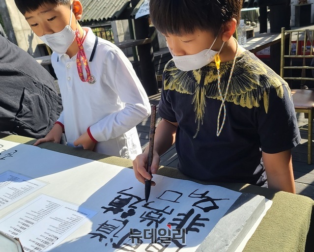 ▲ 한 어린이가 도덕경 베껴 쓰기에 참여해 진지하게 붓글씨를 쓰고 있다.ⓒ김정원 기자