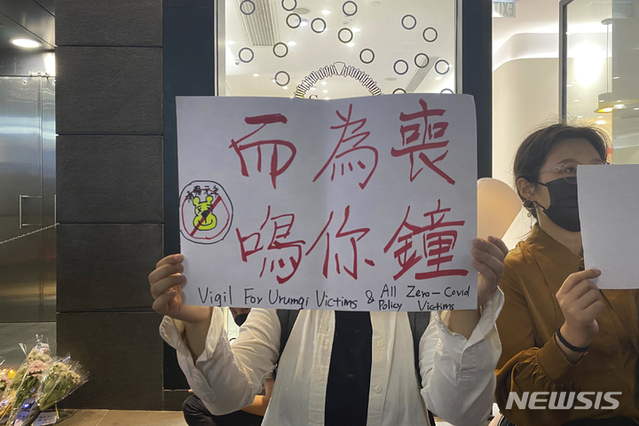 ▲ 한 시위자가 28일 홍콩 중구에서 최근 우루무치 화재의 희생자들을 애도하는 피켓을 들고 있다. 중국 본토의 몇몇 도시에서 집권 공산당을 반대하고 시진핑 주석의 사임을 요구하는 시위가 열리자, 홍콩 학생들은 중국의 코로나 바이러스 통제에 반대하는 시위를 갖고 
