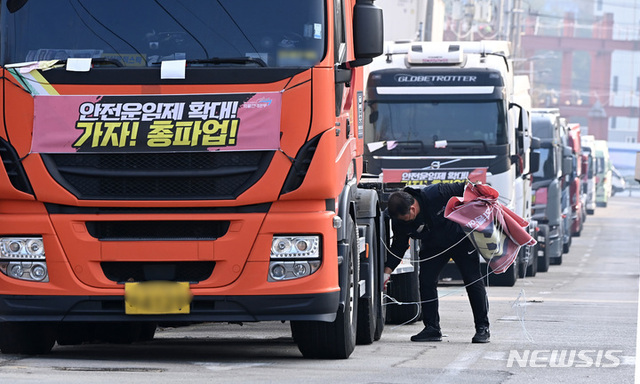 ▲ 화물연대가 총파업을 철회한 9일 오후 경기도 의왕시 내륙컨테이너기지(ICD)앞 도로에 주차된 화물차에서 한 조합원이 현수막을 철거하고 있다. ⓒ뉴시스