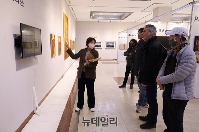 ▲ 포항국제사진제 관계자가 전시된 초청작가 작품을 관람객들에게 설명하고 있다.ⓒ뉴데일리