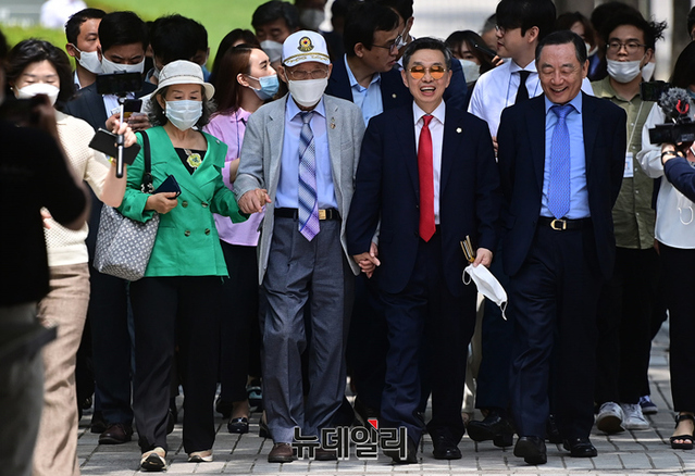 ▲ 북한 김정은을 상대로 낸 손해배상 청구 소송에서 승소한 탈북 국군포로 고 한재복 씨가 2020년 7월 7일 오후 서울 서초구 서울중앙지방법원을 박선영 사단법인 물망초 이사장, 변호인단과 함께 손을 잡고 나서고 있다. ⓒ정상윤 기자