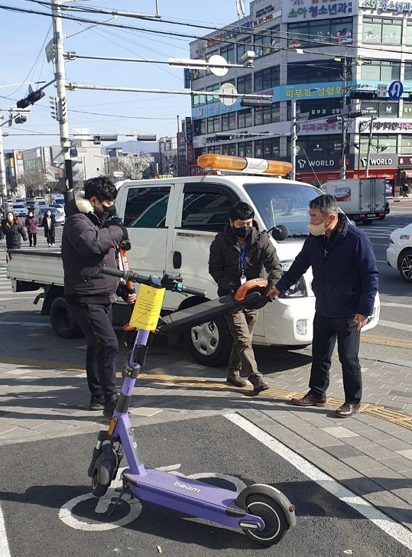 ▲ 천안시 관계자가 보도 내 무단방치된 공유킥보드를 이동조치하고 있다.ⓒ천안시