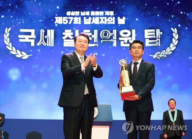 ▲ 윤석열 대통령이 3일 서울 강남구 코엑스에서 열린 제57회 납세자의 날 기념식에서 송호성 기아 대표이사에게 국세 7000억원 고액납세의 탑을 수여한 뒤 축하해 주고 있다. ⓒ연합뉴스