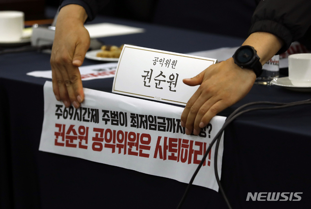 ▲ 지난 18일 서울 프레스센터에서 최저임금위원회 제1차 전원회의를 앞두고 양대노총 관계자들이 권순원 공익위원 자리에 피켓을 붙이고 있다.ⓒ뉴시스