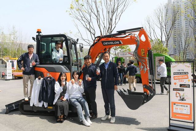 ▲ HD현대 임직원들이 판교 GRC에서 열린 ‘디벨론’ 출시 100일 기념 행사에서 전시된 디벨론 미니굴착기를 배경으로 기념촬영을 하고 있다. ⓒHD현대인프라코어