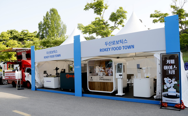 ▲ 두산로보틱스가 17~21일 춘천 라데나 골프클럽에서 운영하는 ‘두산로보틱스 로키(ROKEY) 푸드타운’ 전경 이미지. ⓒ두산로보틱스