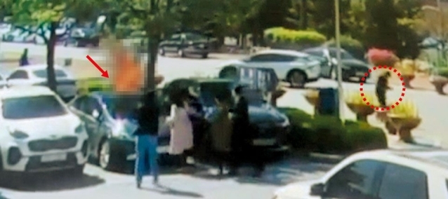 ▲ 지난 1일 오전 춘천지법 강릉지원 주차장 잔디밭에서 민노총 건설노조원 양모(화살표)씨가 자신의 몸에 불을 지르자, 이를 지켜보던 간부 A씨(점선 원)가 구호를 시도하는 대신 반대 방향으로 걸어가며 휴대전화를 조작하고 있다. ⓒ조선일보