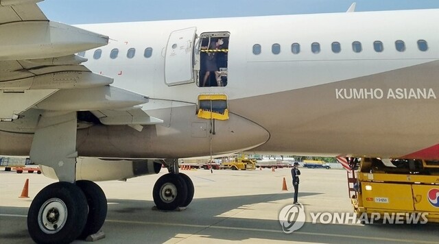 ▲ 지난 26일 오후 제주공항에서 출발해 대구공항에 비상구 출입문이 열린 채 착륙한 아시아나항공기에서 한 승무원이 문에 안전바를 설치한 뒤 두 팔을 벌려 막고 있다. ⓒ연합뉴스