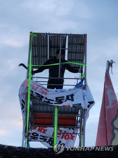 ▲ 31일 오전 전남 광양시 금호동 포스코 광양제철소 인근 도로에서 높이 7ｍ 망루를 설치해 고공농성을 벌인 한국노총 금속노련 간부가 손에 정글도를 들고 있다.ⓒ연합뉴스