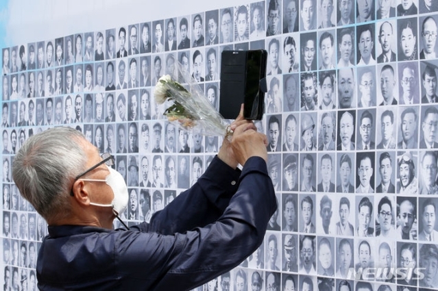 ▲ 28일 오전 경기도 파주시 국립6·25전쟁납북자기념관에서 열린 6·25전쟁 납북희생자 기억의 날 행사에 참석한 한 유가족이 행사장에 걸린 사진을 휴대전화로 찍고 있다. ⓒ뉴시스