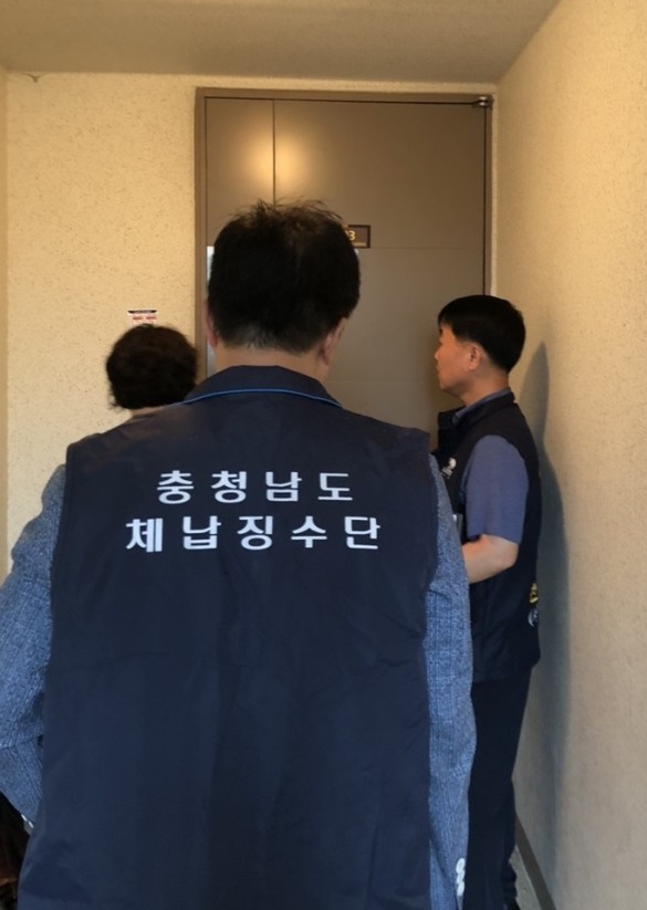 ▲ 충남도 직원들이 고액 체납자  가택 수색을 위해 아파트 입구에서 문 개방을 요구하고 있다.ⓒ충남도